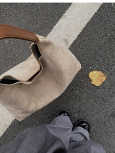 Detailed texture of khaki suede tote bag with contrast brown leather handles