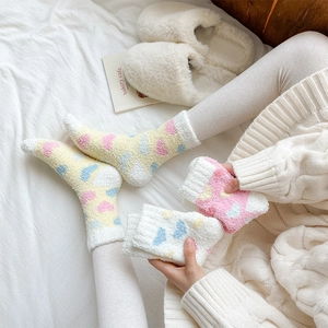 Close-up of cozy coral fleece socks with cute heart patterns for winter home comfort