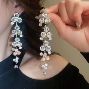 Gros plan de boucles d'oreilles pampilles étincelantes en zircone et dorées sur modèle