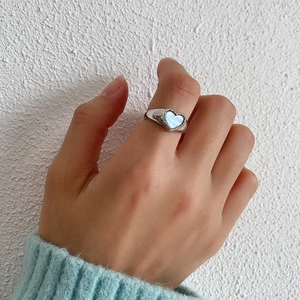 Detail of 925 sterling silver heart ring with shell inlay shown on a woman finger