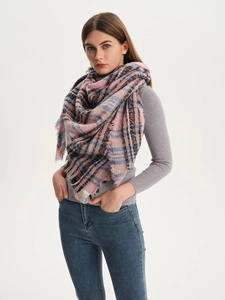 Detail of pink and blue plaid triangle scarf with tassel fringe on a studio model