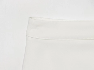 Detailed macro view of white high-waist skirt featuring reinforced stitching and fabric texture