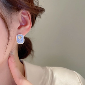 Detail of vintage square tulip earrings with blue base and pearl border on model's ear