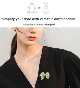 Detail of a gold bow brooch with pearl on a black V-neck top for elegant styling
