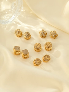 Gros plan de boucles d'oreilles dorées avec zircons sur un tissu en soie beige