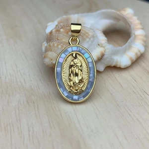 Macro shot of oval gold Virgin Mary pendant with inlaid mother of pearl on wood surface