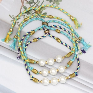 Detail of colorful woven string bracelets with glass pearls and gold metal accents