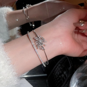 Detail of silver bangle set with starburst floral zircon and pearls on wrist