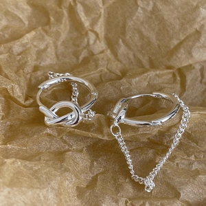 S925 sterling silver knot hoop earrings with chain drop detail on textured background