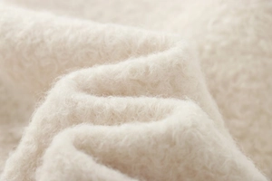 Macro shot of soft white faux shearling fabric showing thick texture and fluffy fibers
