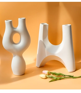 Detail van moderne witte matte keramische vazen met abstracte vormen op een warme achtergrond