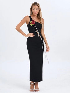 Détail de fleur à paillettes rouges sur robe noire à une épaule et lacets blancs