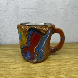Detail of a faux wood coffee mug featuring colorful agate slices and stainless steel lining