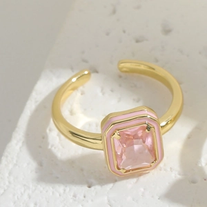 Detail of square pink gemstone ring with enamel border on white textured stone
