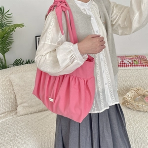 Detailed view of pink canvas tote bag featuring pleated base and large bow shoulder strap