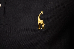 Detailed macro view of the golden giraffe embroidery on black cotton piqué polo shirt