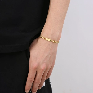 Détail d'un bracelet gourmette en acier inoxydable doré avec une plaque rectangulaire