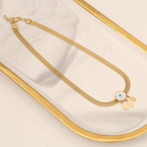 Golden mesh chain necklace with blue eye pendant on white marble display tray