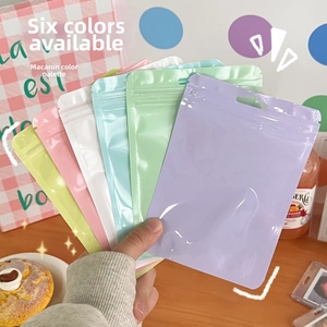 Detailed view of six colorful matte resealable storage bags held in hand for organization