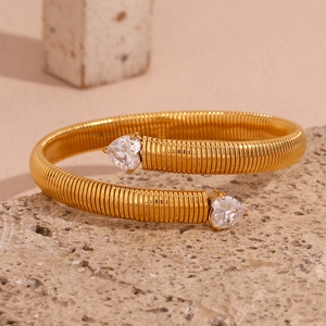 Macro view of gold-plated 18K stainless steel open bangle with ribbed texture and heart stones