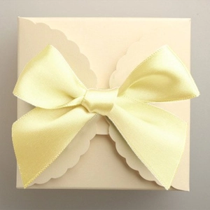 Square cream gift box with decorative bow-cut edge and light yellow satin ribbon