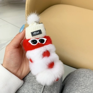 Close-up of red and white caterpillar plush toy with white knit hat and sunglasses