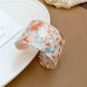 Detail of minimalist irregular resin cuff bracelet with marble texture and open design