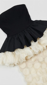 Detailed shot of contrast black bodice and 3D white petal ruffles on a fish tail gown