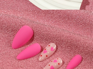 Detail of matte pink and heart-patterned long stiletto press on nails on silk fabric