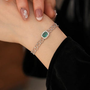 Close-up of vintage bracelet with green oval gemstone and silver beaded lace chain