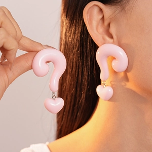 Detail of creative pink resin question mark heart earrings worn on model for sizing