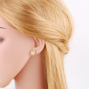 Detailed view of gold spider stud earrings with sparkling cubic zirconia on a model