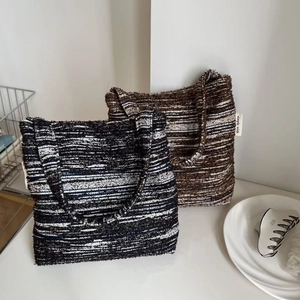 Close-up of thick tweed woven texture on two vintage style small tote bags with side labels