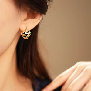 Close-up of golden heart-shaped hoop earrings with leopard print pattern on model