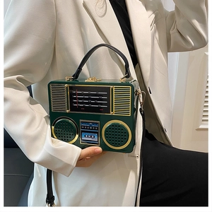 Detail of vintage radio-style acrylic crossbody bag in dark green with gold hardware