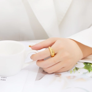 Detail of a vintage golden croissant ring featuring polished spiral textures on a model's finger