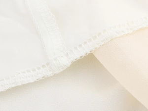 Vue macro des coutures précises et du tissu en mousseline d'une robe blanche élégante