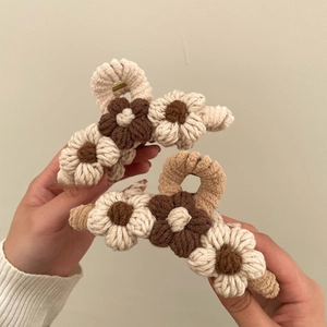 Close-up of two handmade knitted flower hair claws in beige and brown wool yarn