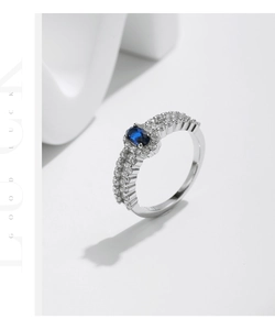 Detailed side view of silver ring featuring oval blue gemstone and double row pave diamonds