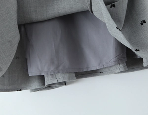 Detail of grey herringbone fabric featuring black butterfly embroidery and smooth inner lining