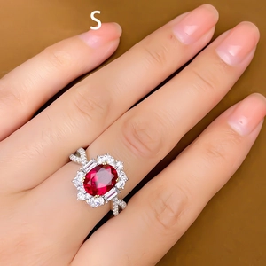 Luxurious open ring featuring oval red corundum center stone and sparkling halo pavé diamonds