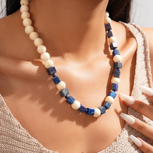 Gros plan du collier bohème avec perles en bois beige et cubes en pierre bleue