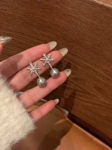 Nahaufnahme von Schneeflocken-Perlenohrringen mit Zirkonia-Inlays handgehalten im Detail
