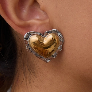 Macro detail of heart stud earrings featuring two-tone gold and textured silver metal