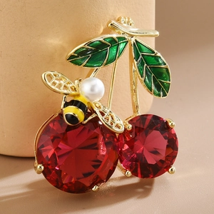 Detailed view of cherry and bee brooch with red gems, green enamel leaves and pearl body
