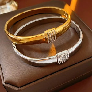 Gros plan de bracelets en acier titane or et argent avec zircons sur un écrin