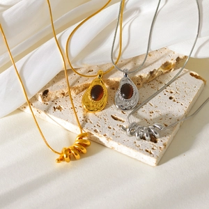 Gold and silver layered necklaces with teardrop gems and spiral pendants on silk