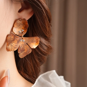 Close-up of amber resin flower earrings with crystals on a model's ear