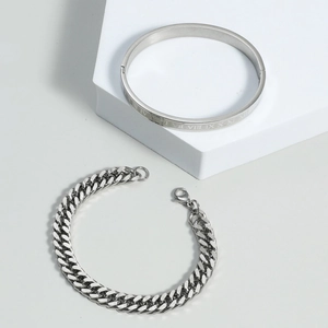 Detail of silver titanium steel cuff with Roman numerals and a Cuban chain bracelet