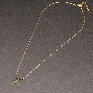 Detail showing the rectangular green gemstone pendant and K18 hallmark on golden chain